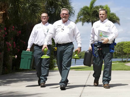 three male safer home service employees working towards the camera with company branded pest control gear