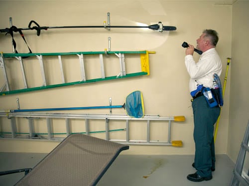 Technician with flashlight looking over garage interior